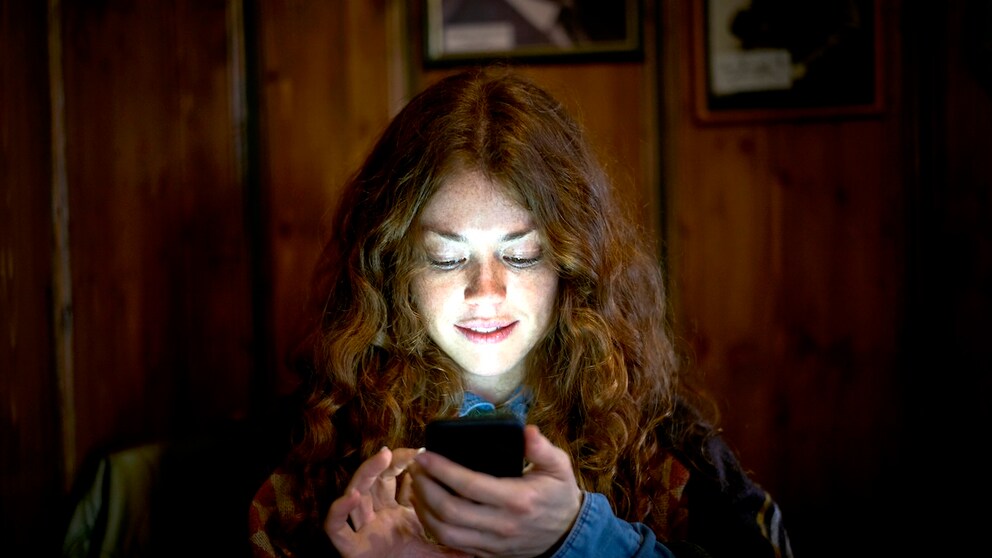 Woman looks at her smartphone in the dark