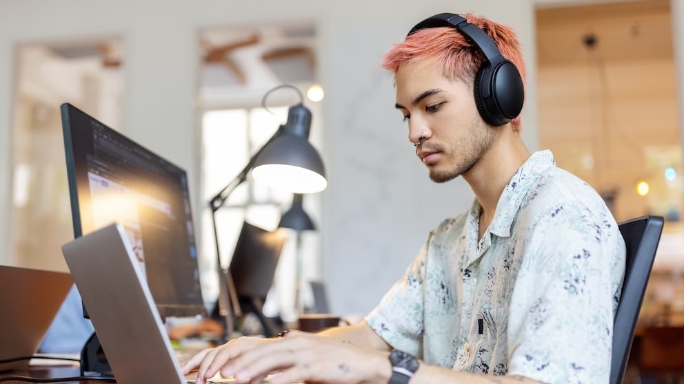 Man with Bluetooth Headphones in Front of a Laptop