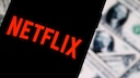 Netflix logo on a smartphone with U.S. dollar bills in the background