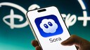 Smartphone with Sora logo and Disney logo in the background