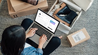 Woman with a computer on her lap. Shoe boxes on the floor.
