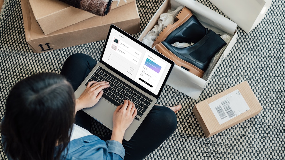 Woman with a computer on her lap. Shoe boxes on the floor.
