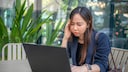 Woman with a stressed expression sits in front of a laptop
