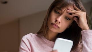 Woman looks exasperatedly at her smartphone