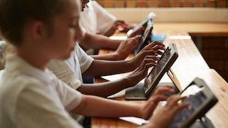 A row of schoolchildren with tablets