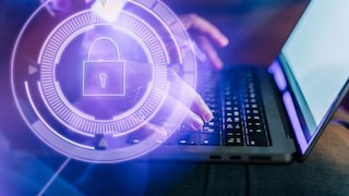 Hands typing on a computer with a security symbol in the foreground