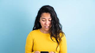 Woman with a confused expression looks at smartphone