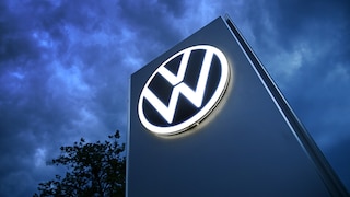 The Volkswagen logo on a pole against a dark sky.