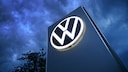 The Volkswagen logo on a pole against a dark sky.