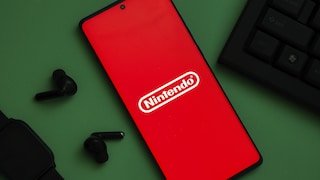 Smartphone with Nintendo Logo Next to Keyboard and Loose Earbuds