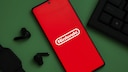 Smartphone with Nintendo Logo Next to Keyboard and Loose Earbuds