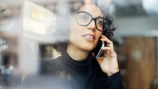 A woman stands by the window, talking on the phone.