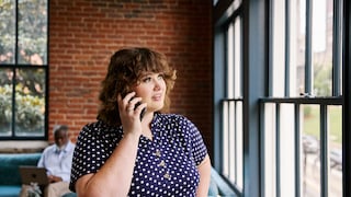 A woman in a café looking out the window while talking on the phone.