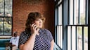 A woman in a café looking out the window while talking on the phone.