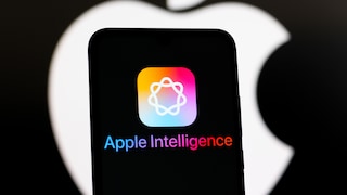 Smartphone with the Apple Intelligence logo and lettering. In the background, a large Apple logo on a black backdrop.