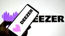 Smartphone with Deezer logo in front of a larger Deezer logo.