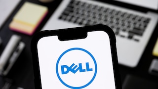 Smartphone with Dell logo, with a notebook in the background.