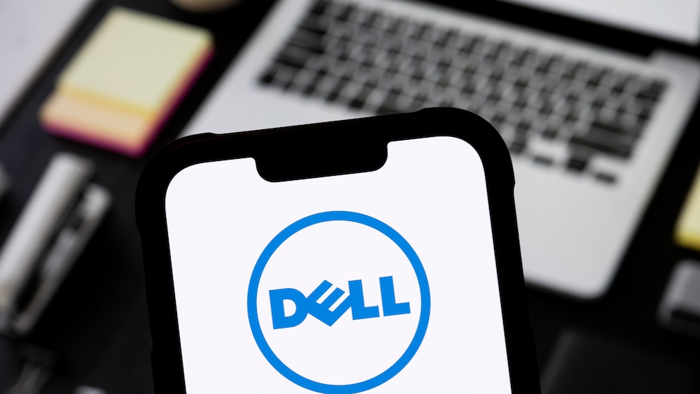 Smartphone with Dell logo, with a notebook in the background.