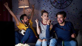 Group of friends cheers on the couch.