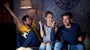 Group of friends cheers on the couch.