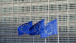 Three waving EU flags in front of the parliament building.