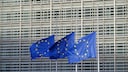 Three waving EU flags in front of the parliament building.