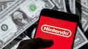 Smartphone with Nintendo logo, with a stack of U.S. dollars in the background.