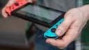 Man holding a Nintendo Switch. One of the Joy-Cons is slightly pushed out at the top.
