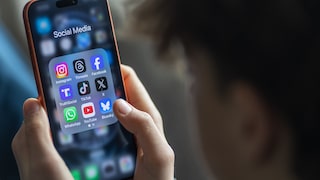 Teenager holds a smartphone displaying numerous social media apps.