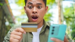 Man Looks Shocked at Credit Card and Smartphone