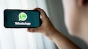 Person with a smartphone displaying the WhatsApp logo.