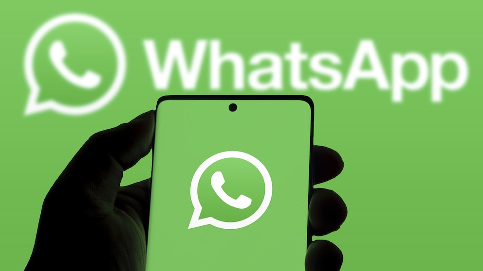 A person holds a smartphone displaying a green screen with the WhatsApp logo. The background is the same green with a second WhatsApp logo.