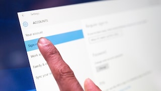 Close-up of a finger touching the "Sign-in options" section under "Accounts" in the Windows settings on a screen