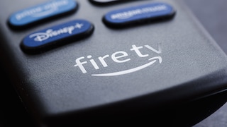 Close-up of a Fire TV remote with a visible Fire TV logo and several blurred buttons for streaming services.