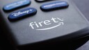 Close-up of a Fire TV remote with a visible Fire TV logo and several blurred buttons for streaming services.