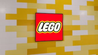 A red Lego logo appears on a rectangular screen in front of a wall made of staggered yellow and white rectangular elements. The logo is centered in the image and surrounded by a black frame. The design of the background wall resembles stacked Lego bricks.