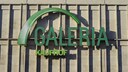 Green Galeria Kaufhof logo on a light stone or concrete facade with vertical structures and visible shadows