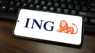 A smartphone lies horizontally on a dark wooden table in front of a black keyboard. The bright screen displays the blue ING logo and the bank's orange lion symbol. The smartphone is slightly angled and occupies most of the image.