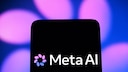 Meta AI logo on a black smartphone display against a blurred blue-violet background with glowing light spots