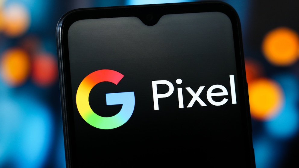 Close-up of a smartphone displaying the colorful Google logo and the word "Pixel" on a black screen. The device is photographed against a blurred background with blue and orange light spots. The image represents Google Pixel smartphones and topics such as Google Pixel 11, pricing, storage options, Android smartphones, and new Pixel models.