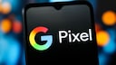 Close-up of a smartphone displaying the colorful Google logo and the word "Pixel" on a black screen. The device is photographed against a blurred background with blue and orange light spots. The image represents Google Pixel smartphones and topics such as Google Pixel 11, pricing, storage options, Android smartphones, and new Pixel models.