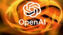 The OpenAI logo appears in white against a blurred background of orange and yellow light streaks. Below the logo, the word "OpenAI" is displayed in white lettering. The image is dominated by warm orange tones and, due to the strong blur in the background, has an abstract feel.