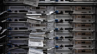 The backs of several stacked servers in a data center, with connected network cables and ports in the server racks.