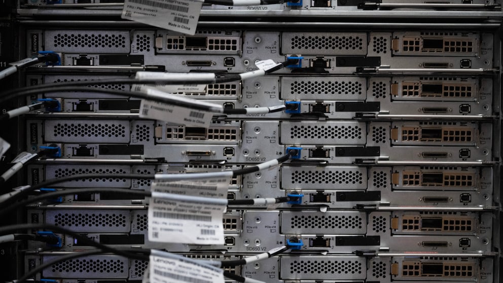 The backs of several stacked servers in a data center, with connected network cables and ports in the server racks.