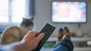 Person watches TV and points a remote control at the television