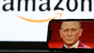 A smartphone displays an image of a James Bond actor. In the blurred background, the Amazon logo is prominently visible. The photo illustrates Amazon's involvement in the future of the James Bond franchise.