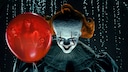 Clown Pennywise grins directly at the camera