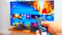 TV remote in the foreground, blurred television in the background