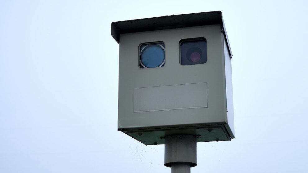 A speed camera is positioned by the roadside.