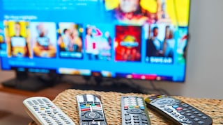 Several remote controls are lying on a table in front of a television.